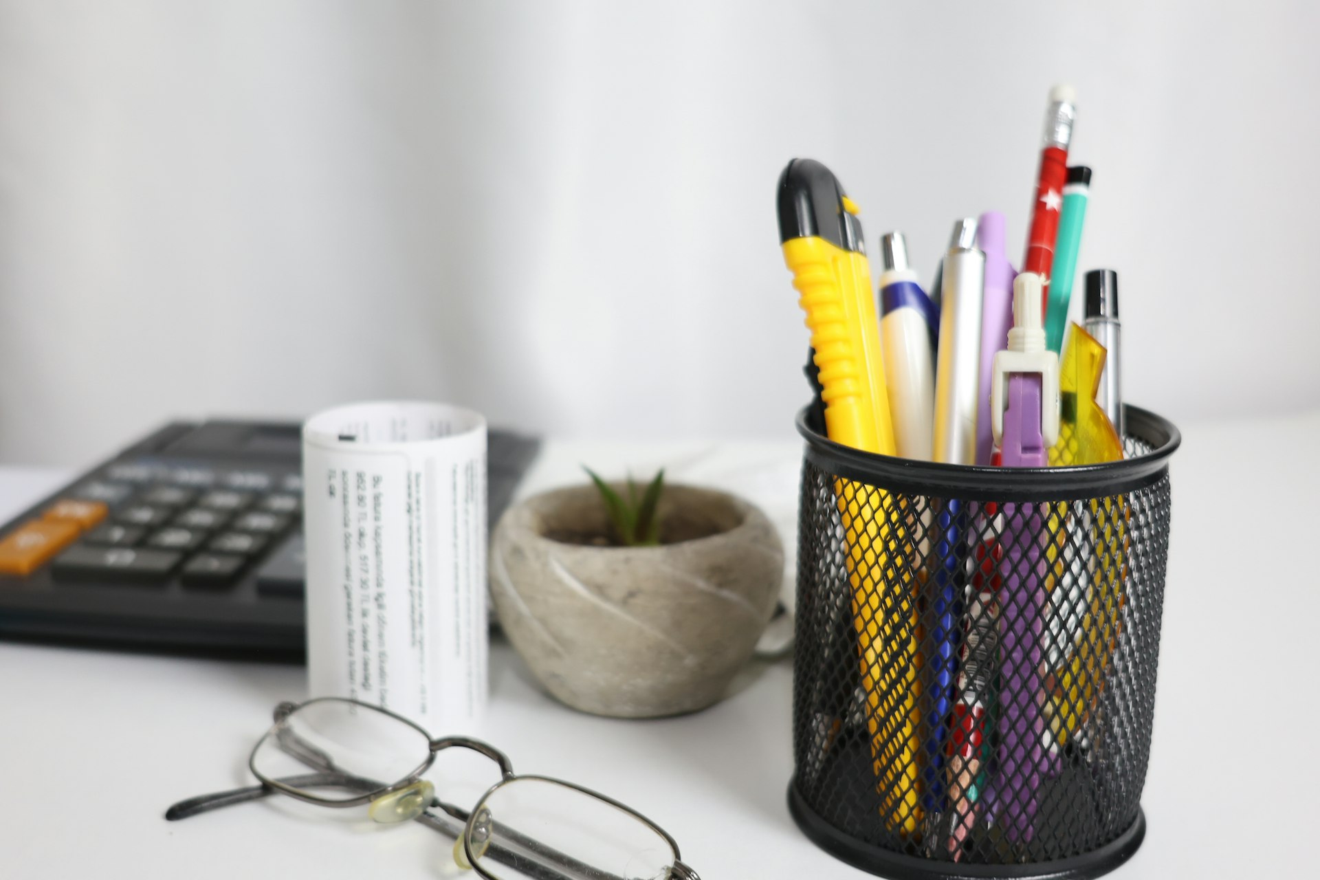 Desk with calculator, pens, and glasses